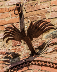 Phoenix-like, this iron bird prepares to rise from arch perch.