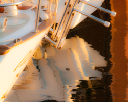 An outboard motor becomes sculptural through its harbor reflections.