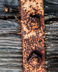 Pitted iron still clings to grooved and weathered wood.