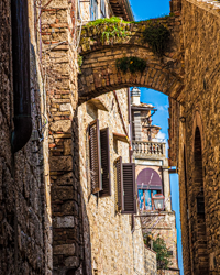 Ancient arches create chiaroscuro light in the narrow streets of an Italian hill town.