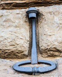 A simple medieval torch holder sits in its chiseled stone niche.