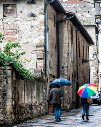 Umbrella colors brighten the stony gray of an Italian back street.